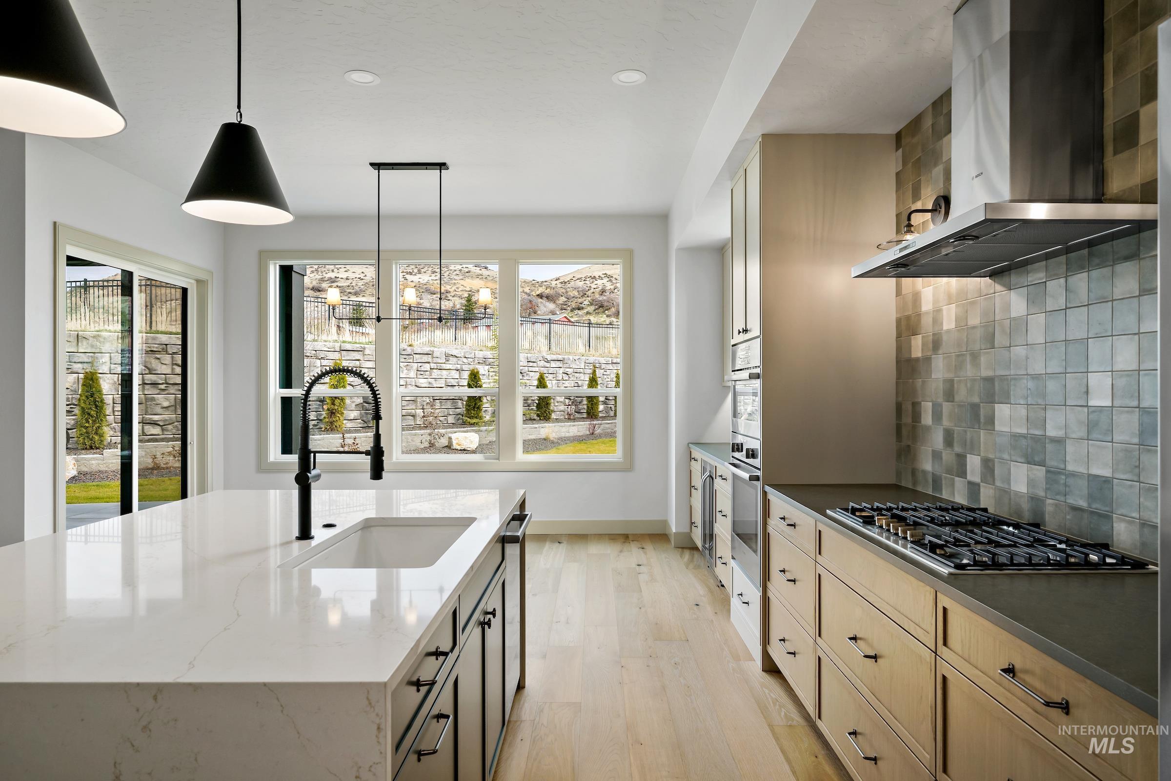 11696 North Rabbitbrush Way Boise, ID 83714 - Photo 3 of 32 Kitchen with wall chimney range hood, pendant lighting, decorative backsplash, recessed lighting, and dark stone countertops
