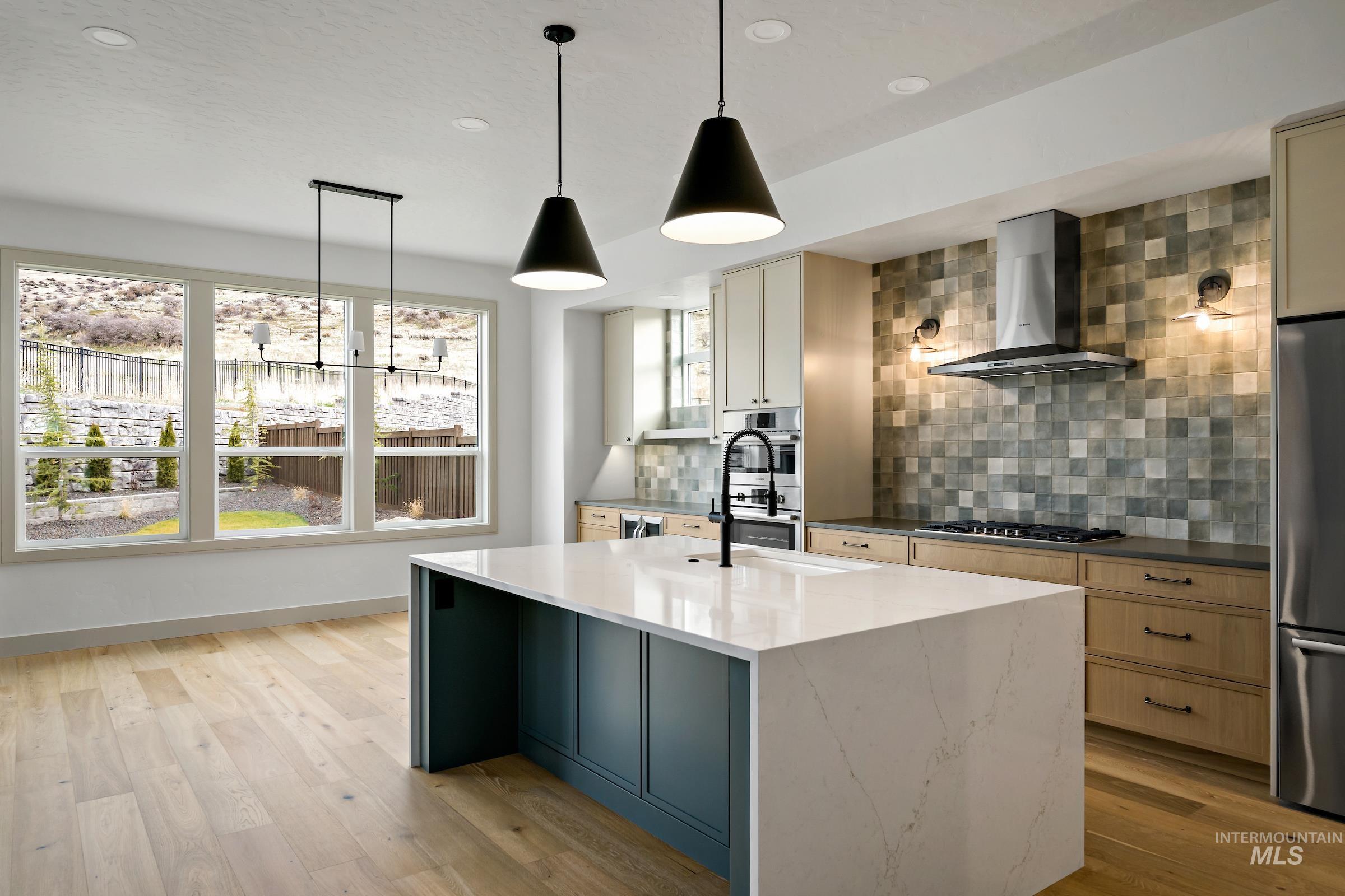 11696 North Rabbitbrush Way Boise, ID 83714 - Photo 6 of 32 Kitchen featuring wall chimney range hood, tasteful backsplash, decorative light fixtures, light wood-style floors, and recessed lighting