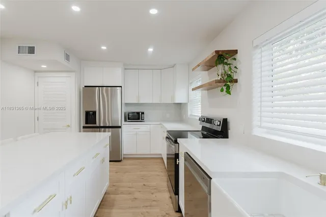 a kitchen with a refrigerator a stove top oven a sink and a window