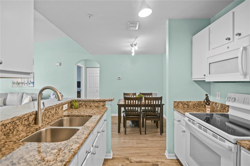 7417 Vista Way, Unit 202 Lakewood Ranch, FL 34202 - Photo 12 of 56 a kitchen with a stove a sink a dining table and chairs