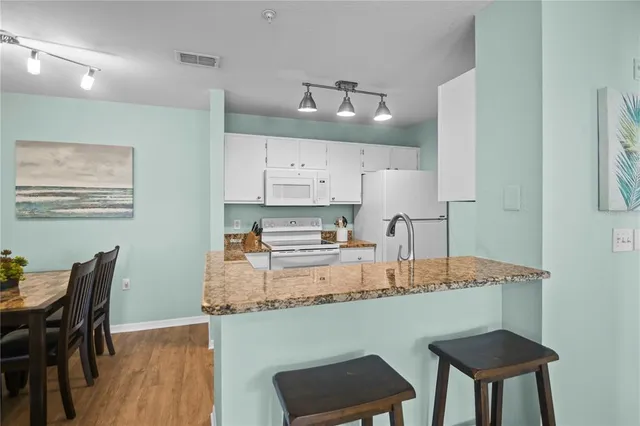 a kitchen with granite countertop a table chairs stove and cabinets