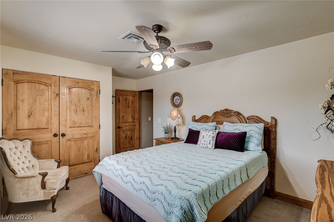 1950 Bowman Road Logandale, NV 89021 - Photo 43 of 81 This cozy bedroom features a practical ceiling fan, ample storage in wooden closets, and plush carpeted flooring.