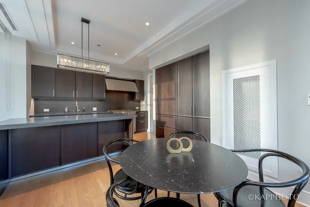 a kitchen with kitchen island granite countertop a sink a stove cabinets dining table and chairs