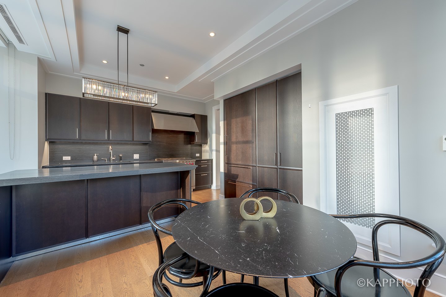118 East Erie Street, Unit 15A Chicago, IL 60611 - Photo 18 of 28 a kitchen with kitchen island granite countertop a sink a stove cabinets dining table and chairs