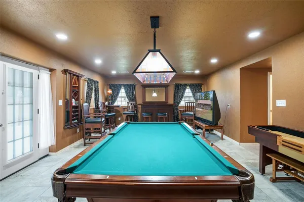 a room with furniture pool table wooden floor and windows