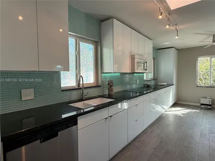 a large kitchen with granite countertop a sink window and cabinets