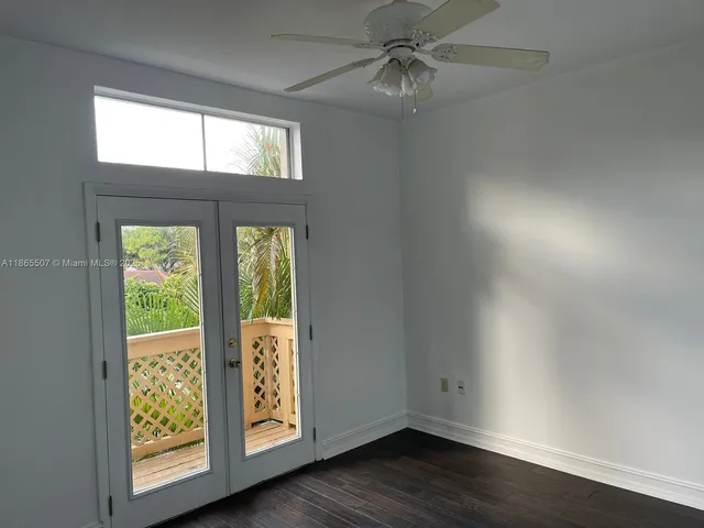 an empty room with wooden floor fan and windows