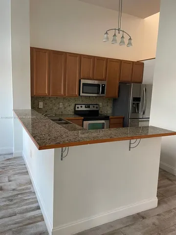 a kitchen with kitchen island a counter top a stove and a chandelier