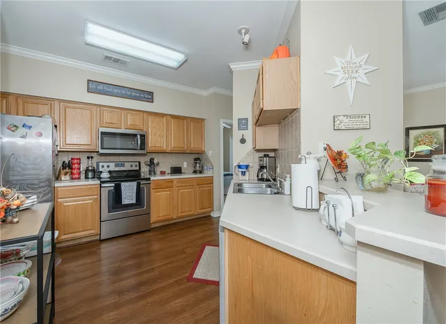 a kitchen with granite countertop a refrigerator a sink dishwasher stove and oven with wooden floor