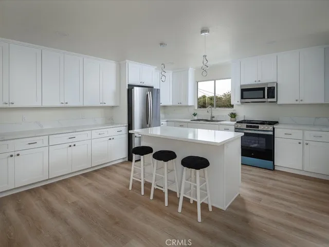 a kitchen with stainless steel appliances kitchen island granite countertop a table chairs microwave and sink