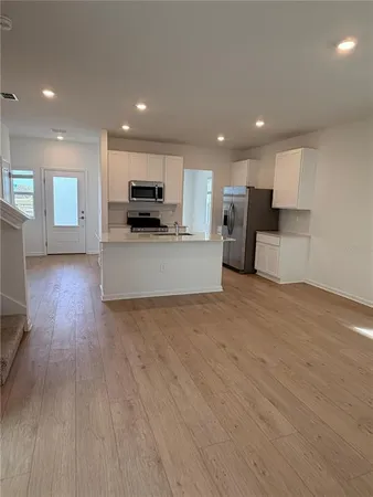 a view of kitchen with kitchen island microwave and wooden floor