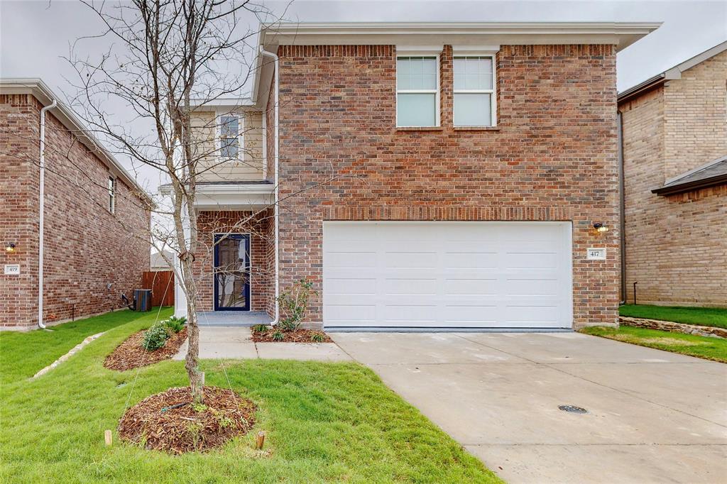 Traditional-style home with brick siding, driveway, a garage, and a front lawn
