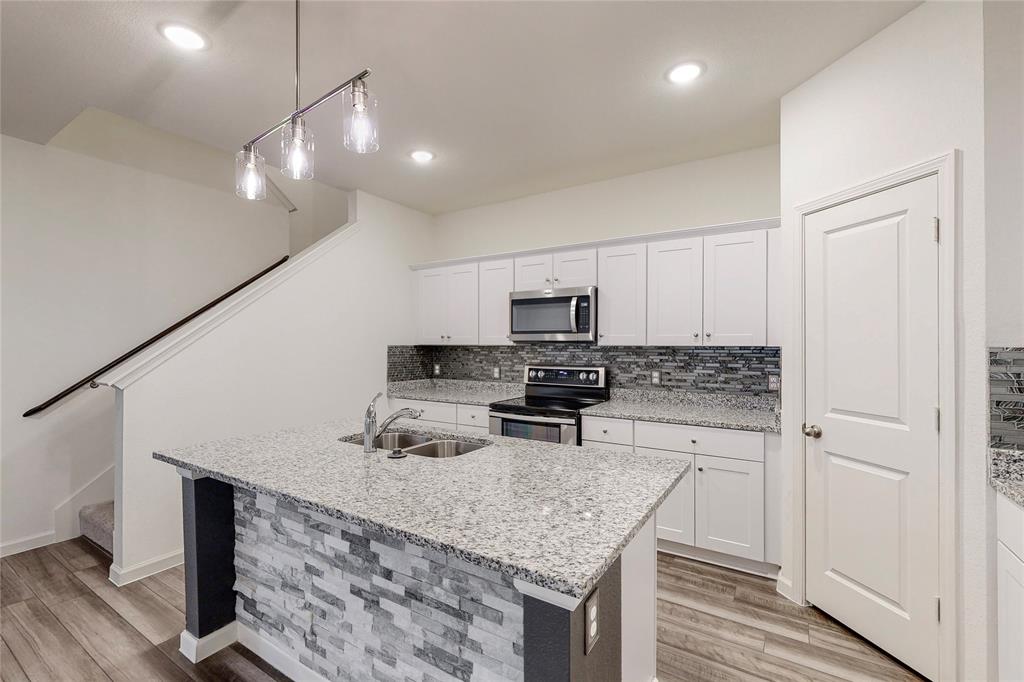 417 Madison Way Princeton, TX 75407 - Photo 11 of 40 Kitchen featuring light wood-style flooring, light stone countertops, pendant lighting, white cabinets, and stainless steel appliances