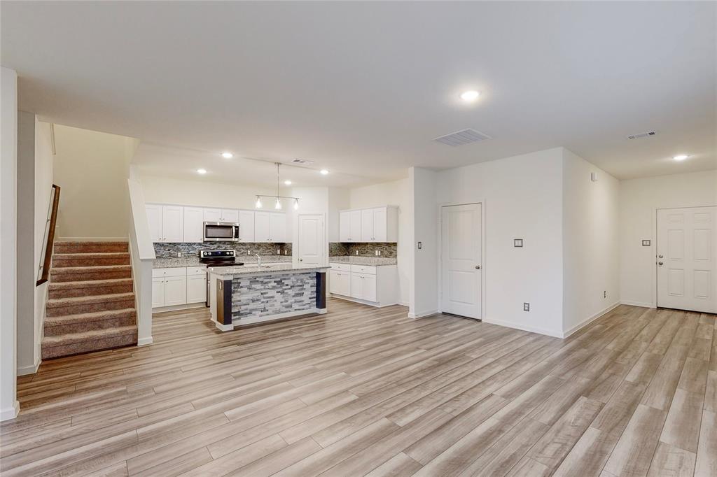417 Madison Way Princeton, TX 75407 - Photo 39 of 40 Kitchen featuring white cabinetry, open floor plan, a kitchen island with sink, recessed lighting, and backsplash
