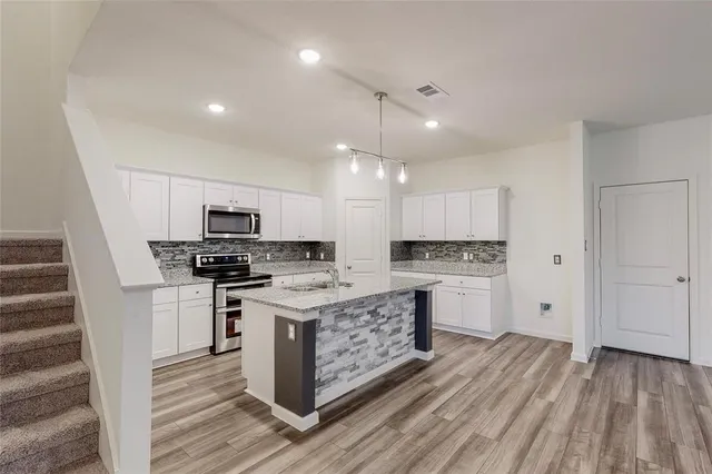 a view of kitchen with cabinets stainless steel appliances and wooden floor