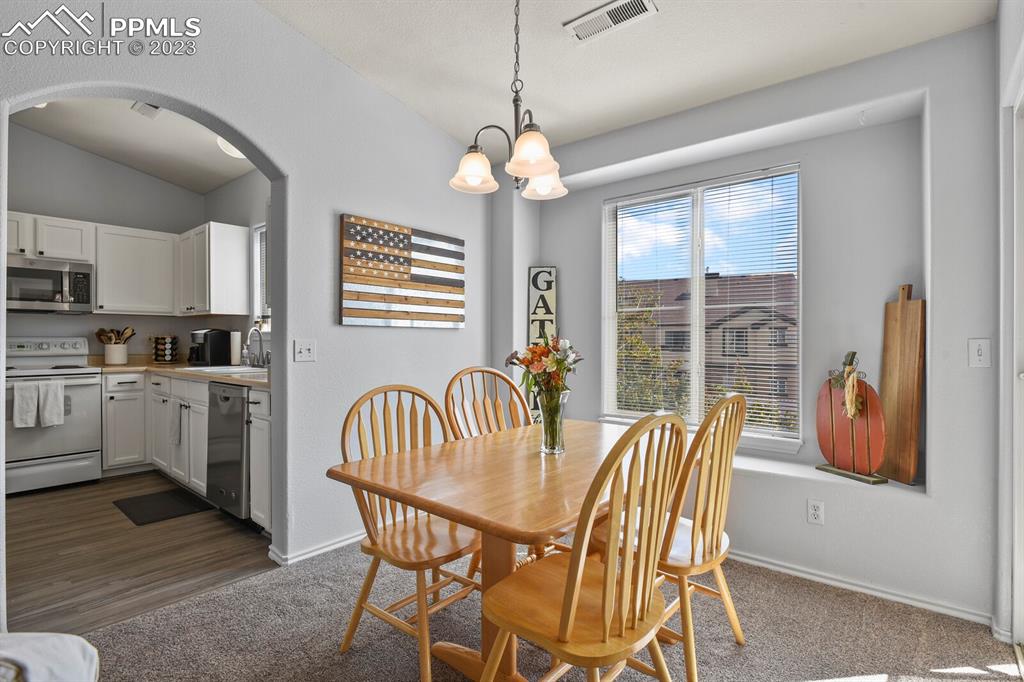 3960 Riviera Grove, Unit 204 Colorado Springs, CO 80922 - Photo 13 of 25 a dining room with furniture a chandelier and window