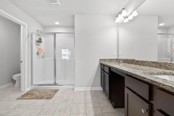 a bathroom with a granite countertop sink a toilet and shower