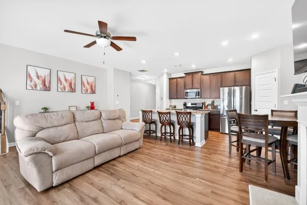 a living room with furniture kitchen and a wooden floor