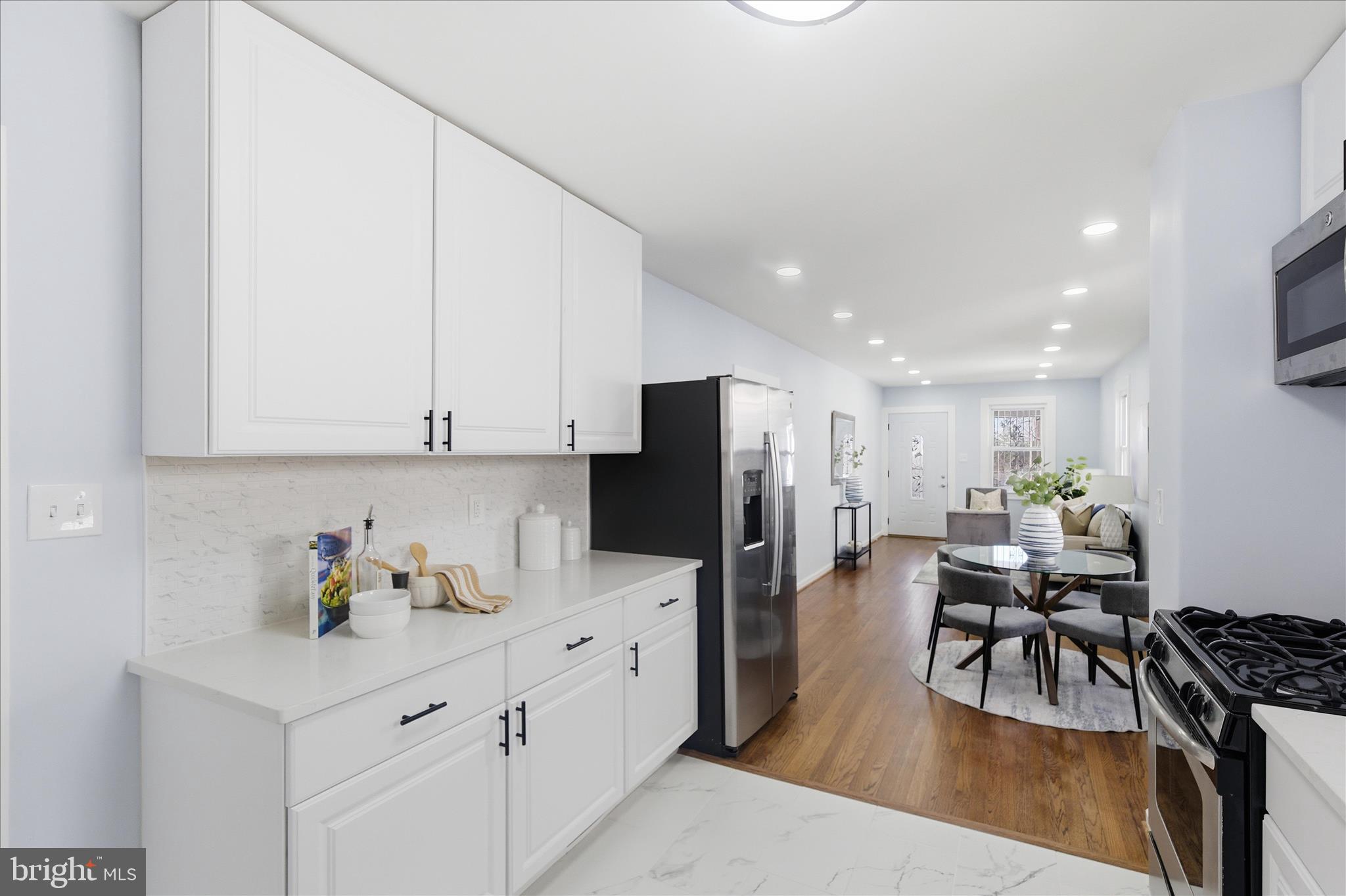 4029 Gault Place Northeast Washington, DC 20019 - Photo 10 of 33 a kitchen with stainless steel appliances kitchen island granite countertop a refrigerator oven a sink a dining table and chairs with wooden floor