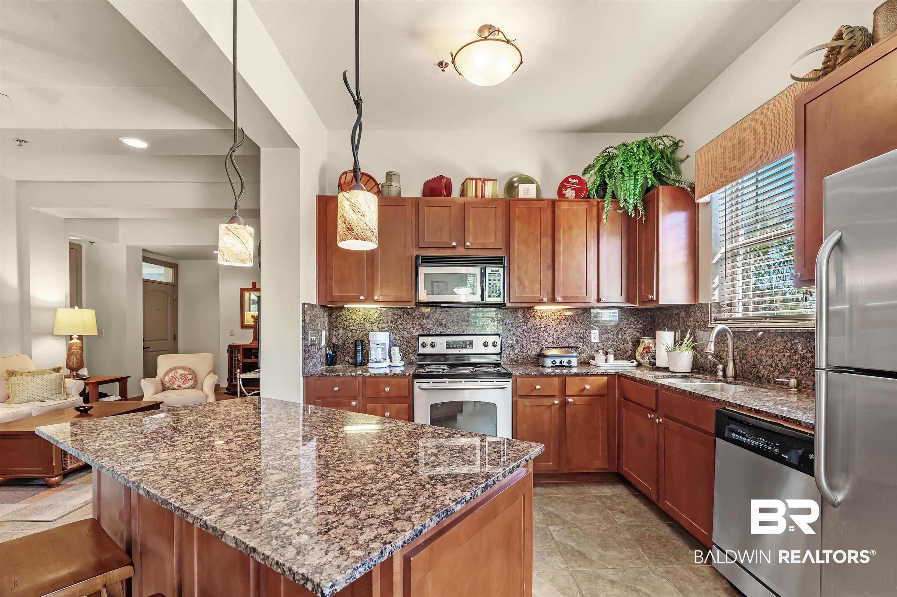 1430 Regency Road, Unit A301 Gulf Shores, AL 36542 - Photo 17 of 47 Kitchen with tasteful backsplash, appliances with stainless steel finishes, dark stone countertops, pendant lighting, and a center island