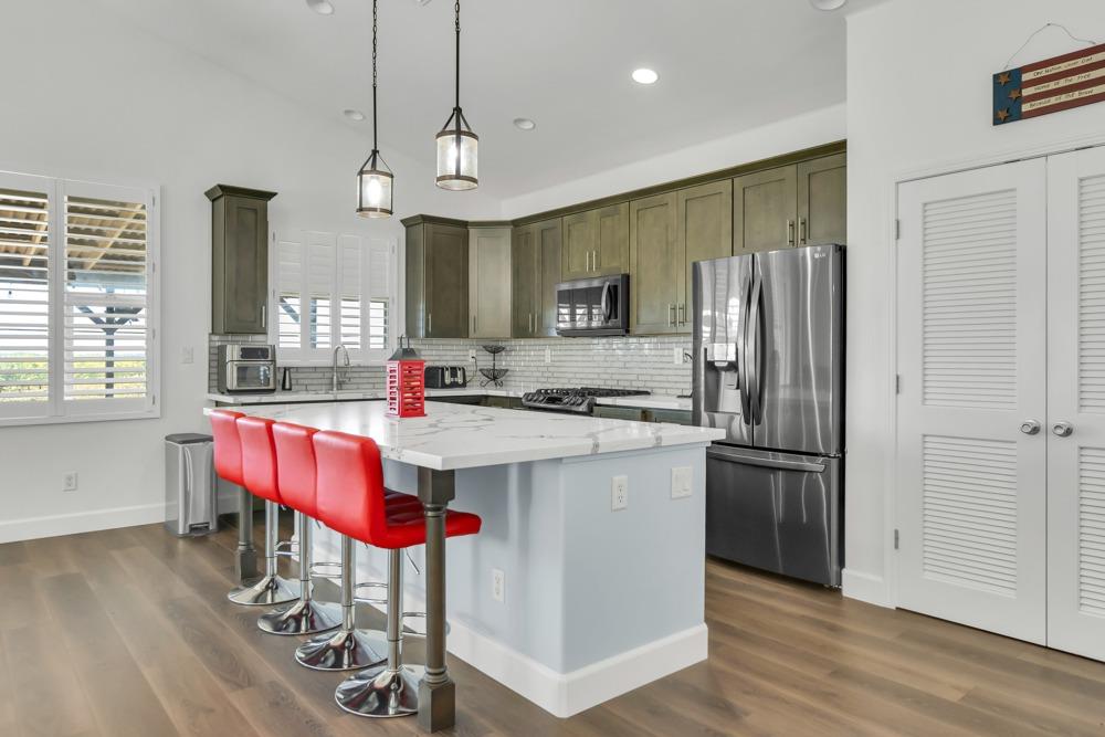 32852 South River Road Clarksburg, CA 95612 - Photo 15 of 72 a kitchen with kitchen island granite countertop a refrigerator a stove a sink dishwasher a dining table and chairs with wooden floor