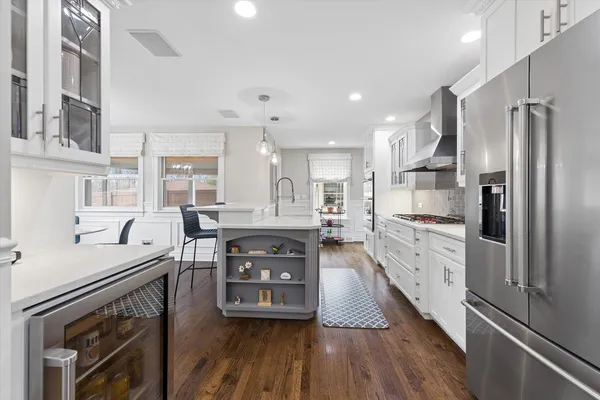 a kitchen with stainless steel appliances granite countertop a refrigerator a stove and a wooden floors