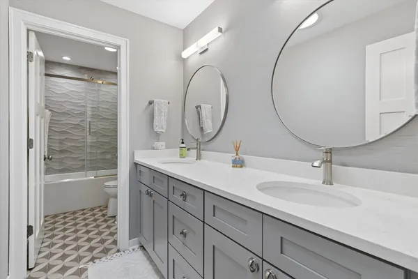 a bathroom with a double vanity sink mirror and bathtub