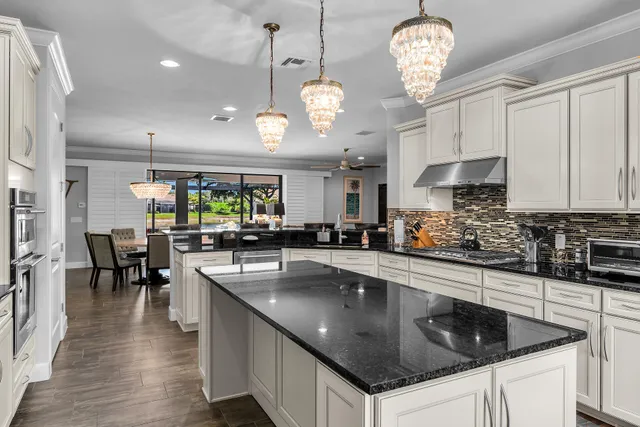 a kitchen with stainless steel appliances granite countertop a sink a stove and a wooden floors