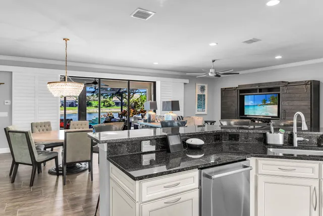 a kitchen with stainless steel appliances kitchen island granite countertop a stove a sink a refrigerator and white cabinets with wooden floor