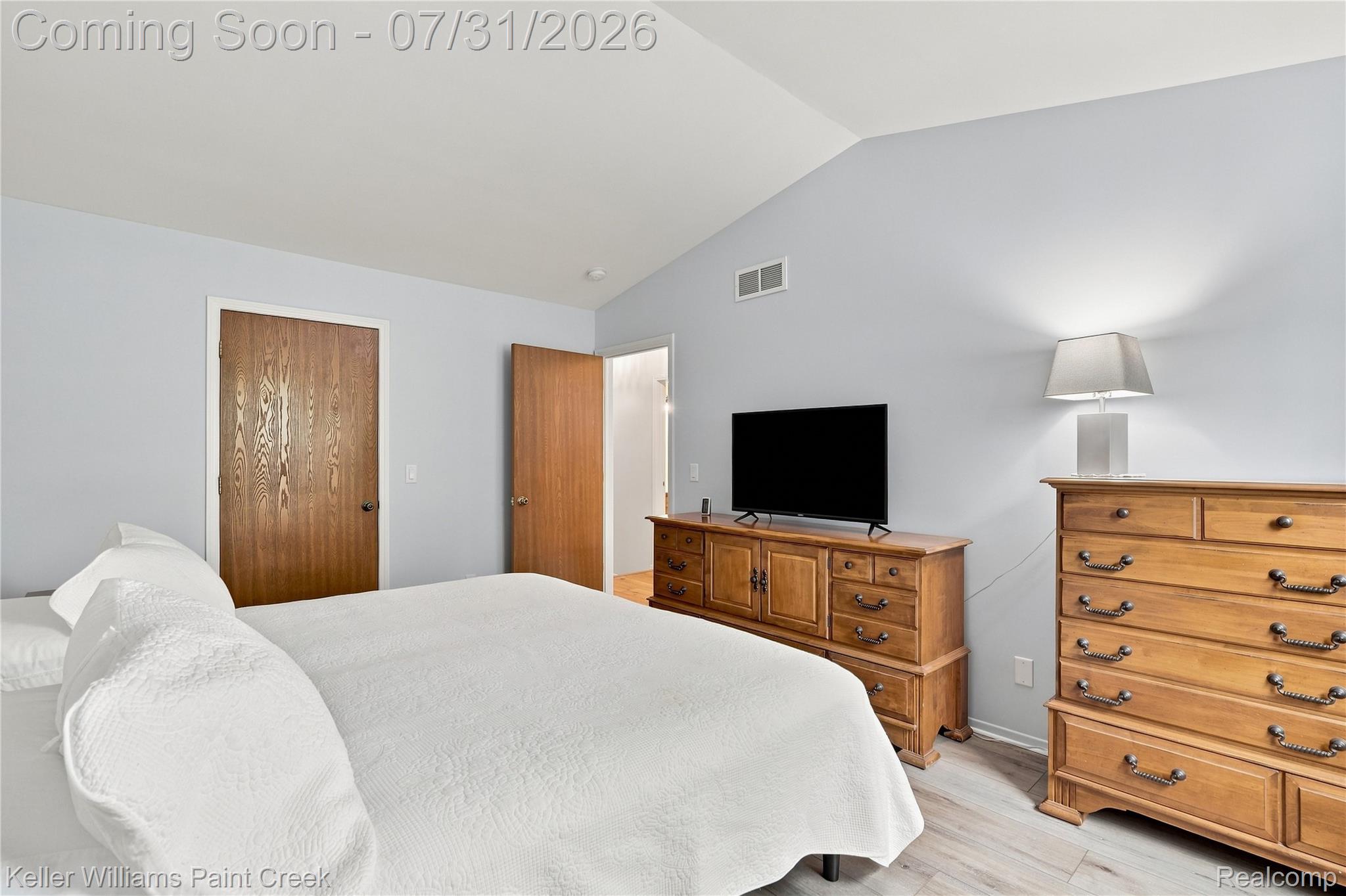 3009 High Pointe Ridge Road Lake Orion, MI 48359 - Photo 13 of 21 Vaulted ceiling bedroom with light blue walls, wood-finish flooring, and two wood-paneled doors