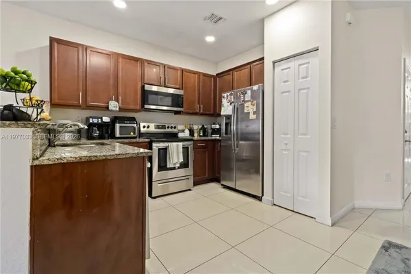 a kitchen with stainless steel appliances granite countertop a refrigerator a sink a stove top oven and a dishwasher