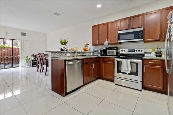 a kitchen with stainless steel appliances granite countertop a stove top oven a sink dishwasher and white cabinets