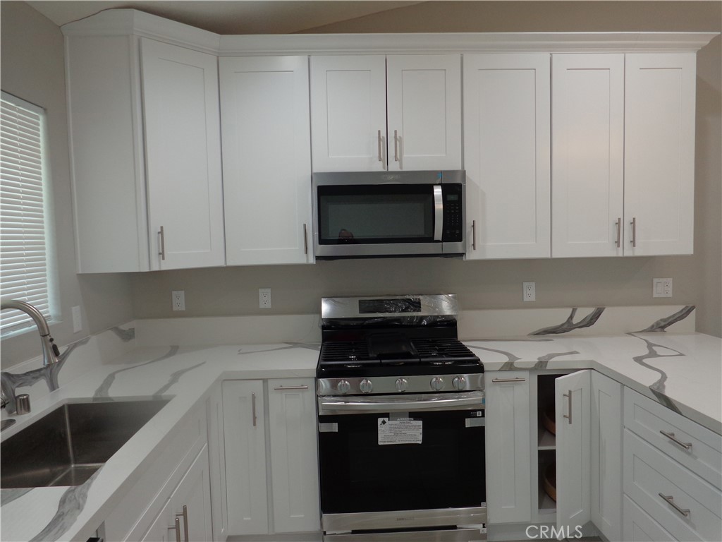 12744 Running Deer Road Apple Valley, CA 92308 - Photo 8 of 30 a kitchen with granite countertop white cabinets a sink and dishwasher