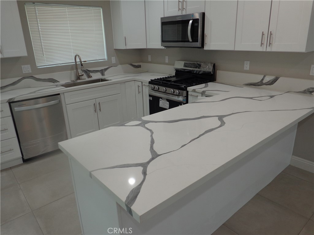 12744 Running Deer Road Apple Valley, CA 92308 - Photo 10 of 30 a kitchen with stainless steel appliances a sink dishwasher stove refrigerator and microwave
