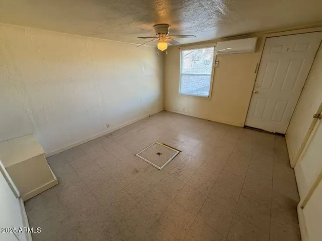 an empty room with windows and fan