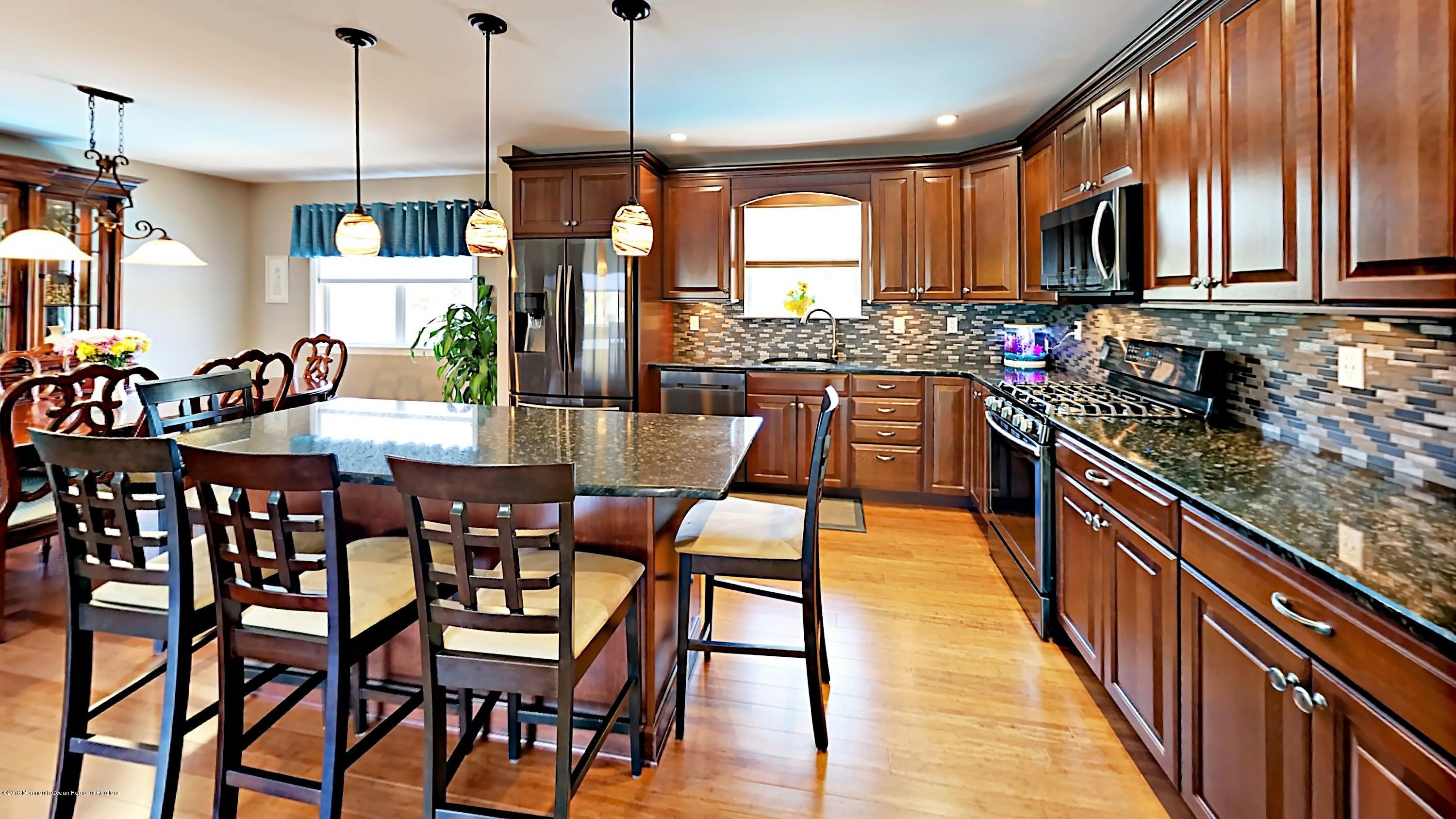 30 Netty Street Howell, NJ 07731 - Photo 4 of 24 a kitchen with stainless steel appliances granite countertop a stove top oven a sink a dining table and chairs with wooden floor