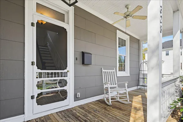 an empty room with wooden floor chandelier fan and windows