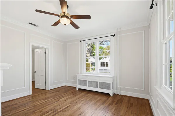 a view of an empty room with window and wooden floor