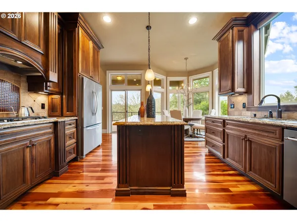 a kitchen with stainless steel appliances granite countertop a stove top oven a sink dishwasher a dining table and chairs with wooden floor