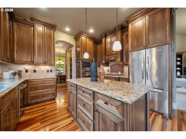 a kitchen with kitchen island granite countertop wooden cabinets and a refrigerator