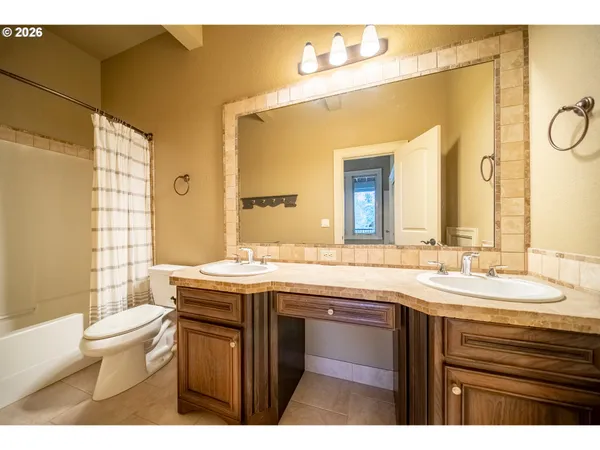 a bathroom with a granite countertop sink a toilet a mirror and shower