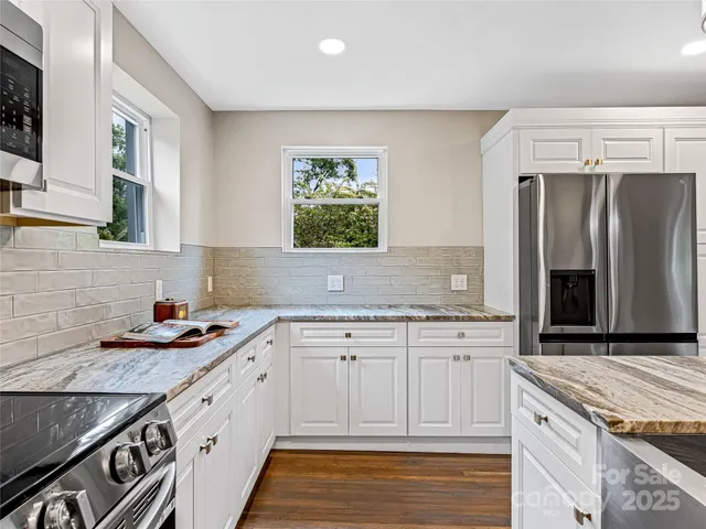 a kitchen with granite countertop stainless steel appliances a sink stove refrigerator and cabinets