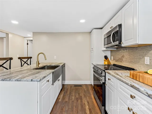 a kitchen with stainless steel appliances granite countertop a sink stove and microwave