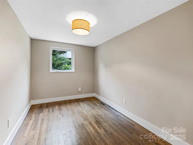 an empty room with wooden floor and window