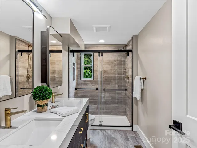 a bathroom with a granite countertop sink a mirror and shower