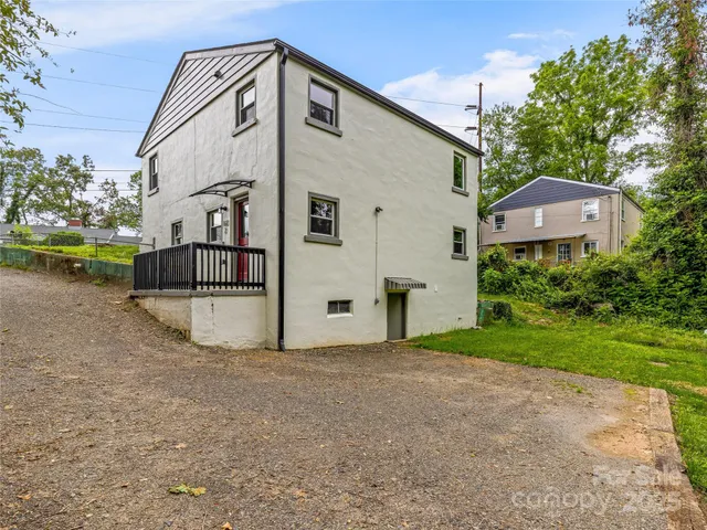 a view of a white house with a big yard and large trees