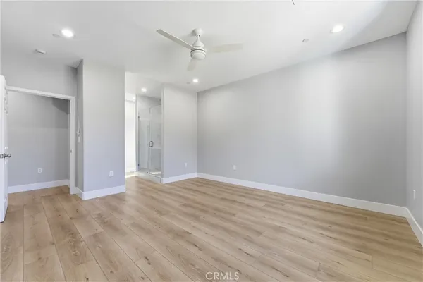 an empty room with wooden floor and ceiling fan