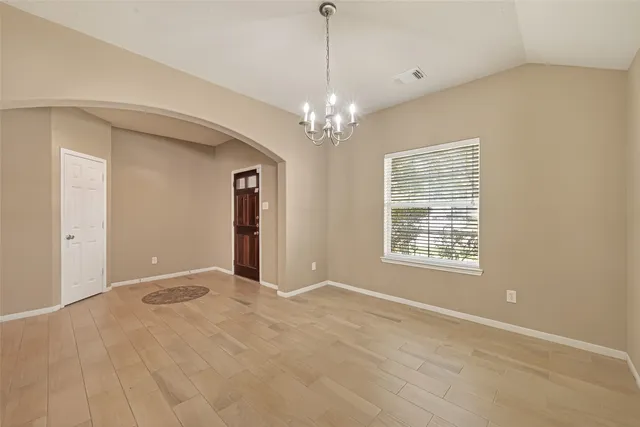 a view of an empty room with chandelier and a window