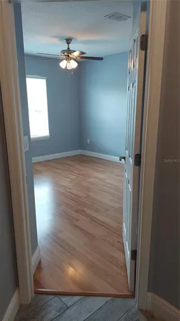 en empty room with wooden floor and fan