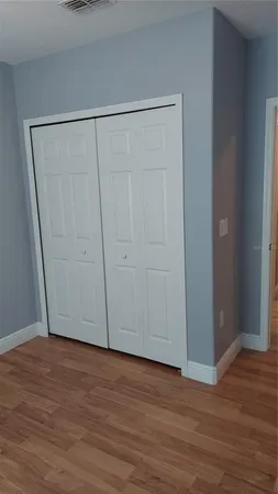 a view of an empty room with wooden floor and closet